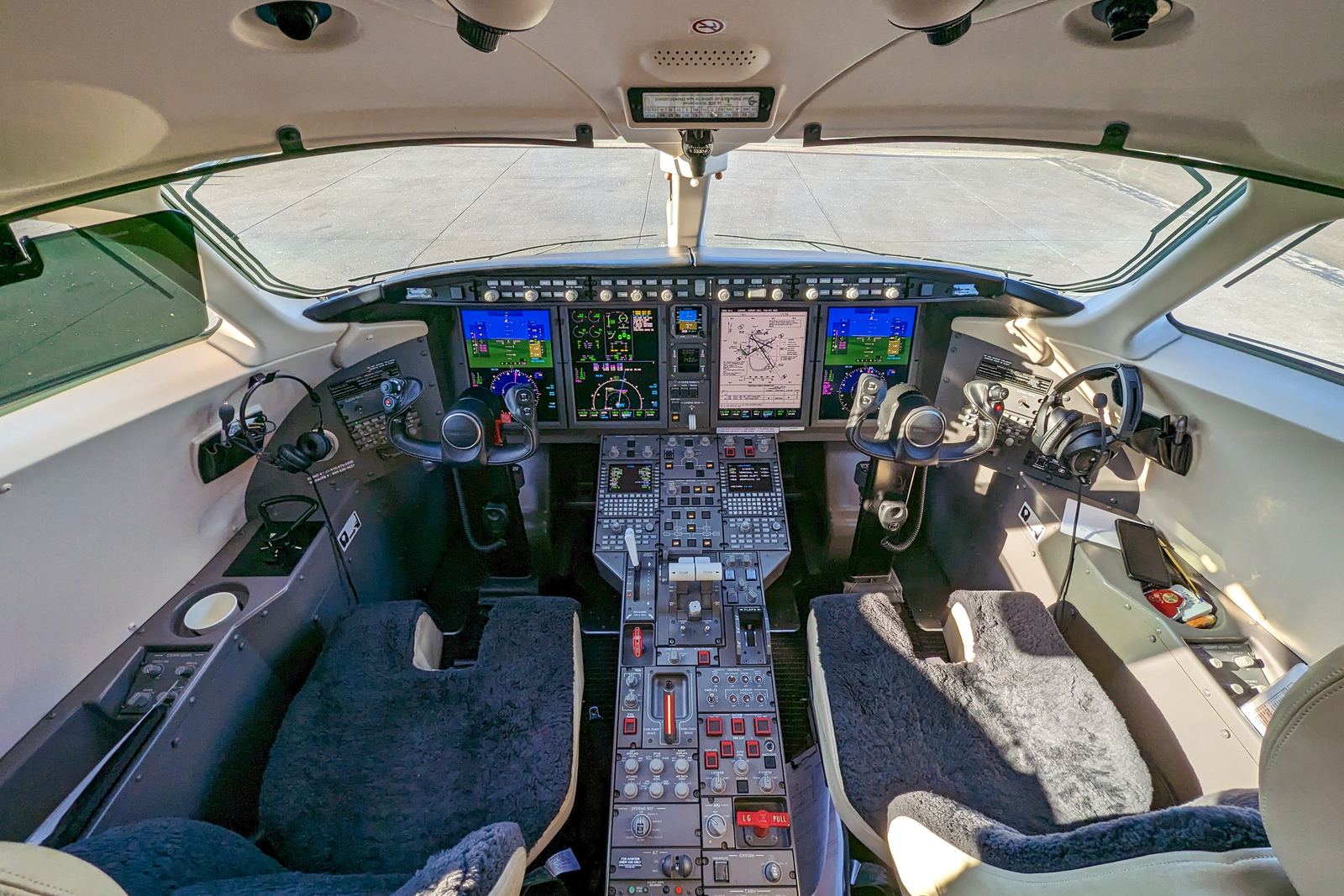 A business jet flight deck seen from behind the seats.