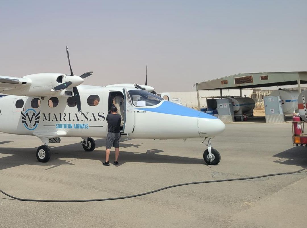 A Tecnam P2012 Traveller in an operator's livery on a hazy ramp.