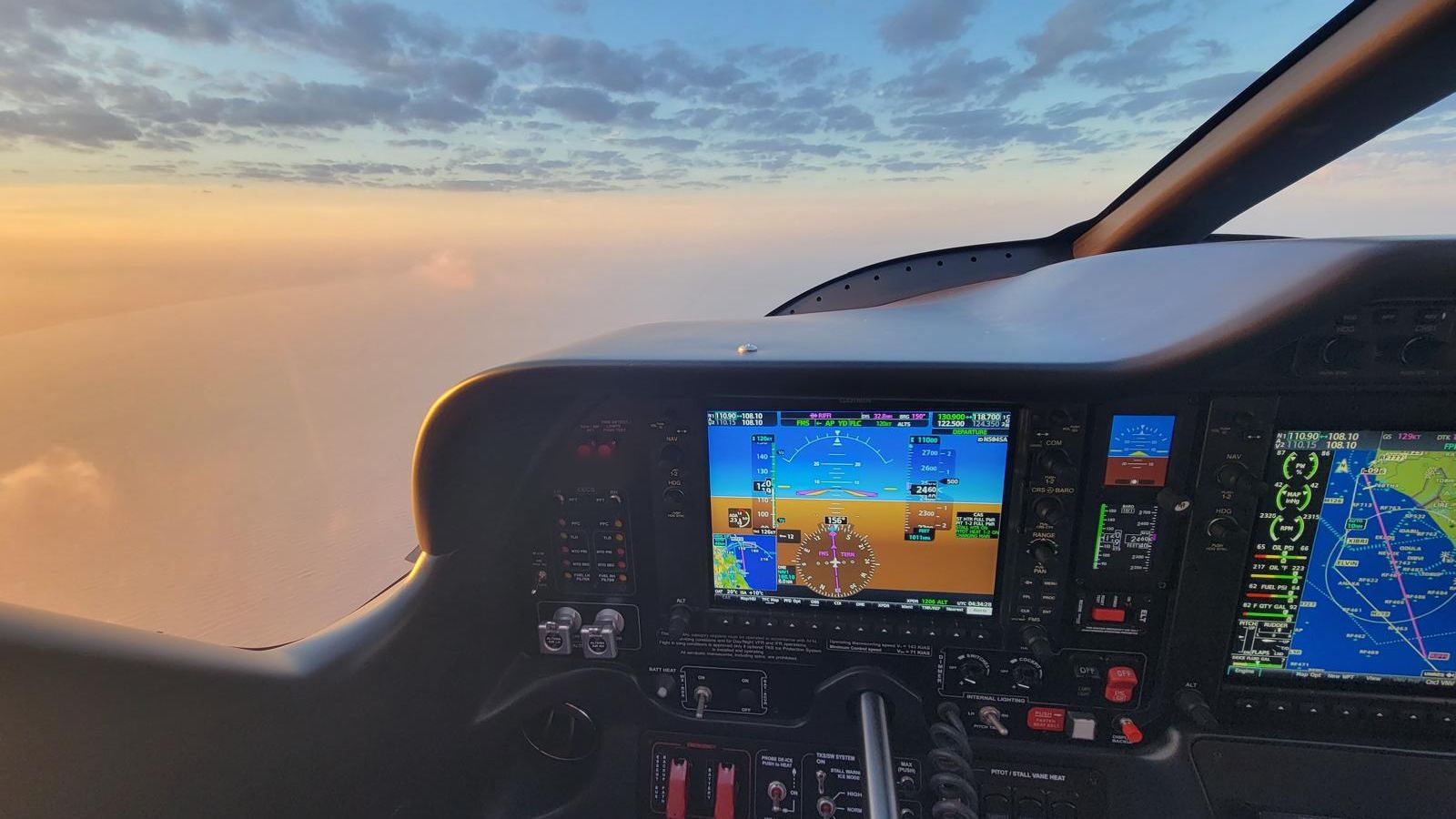 A Garmin glass cockpit at sunset, above the cloud.