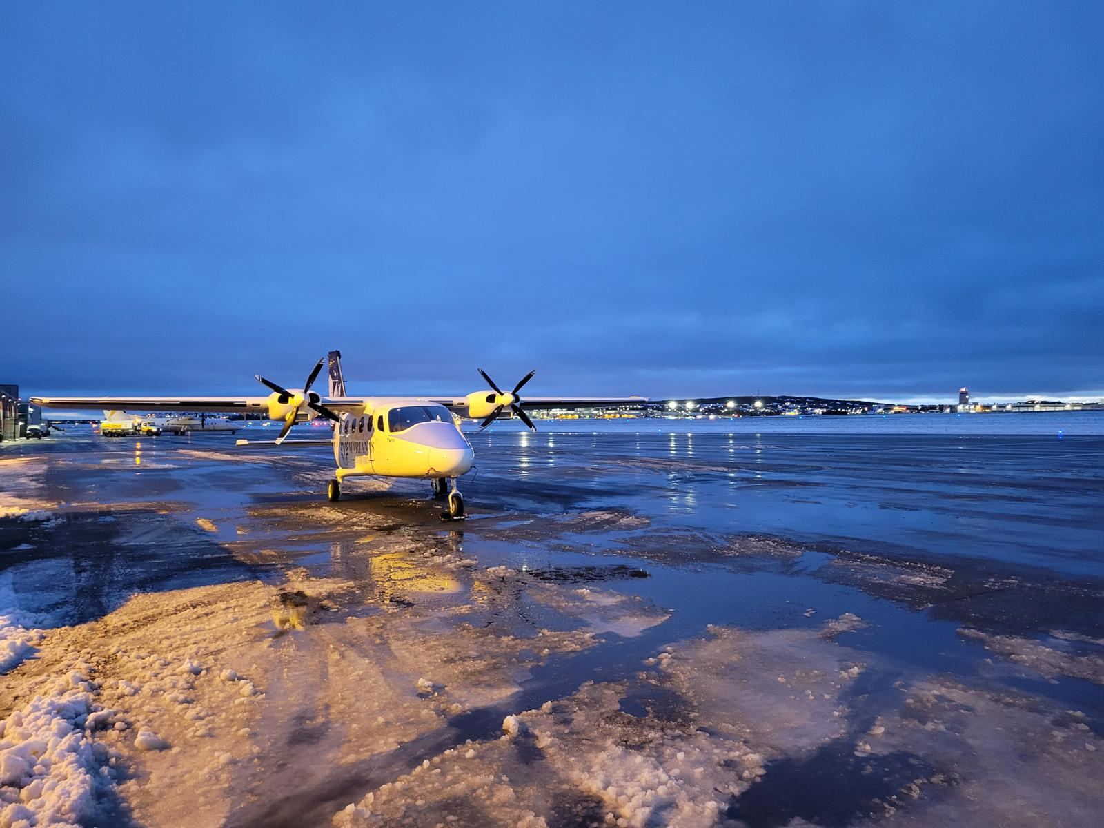 A Tecnam P2012 nose-on at dusk on an icy apron.