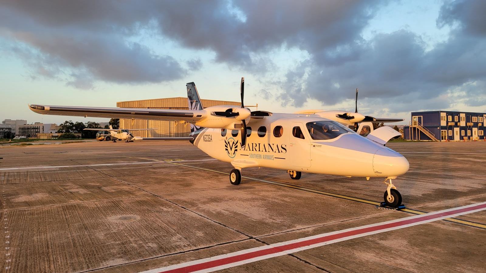A Tecnam P2012 Traveller on a ramp in golden evening light under storm clouds.