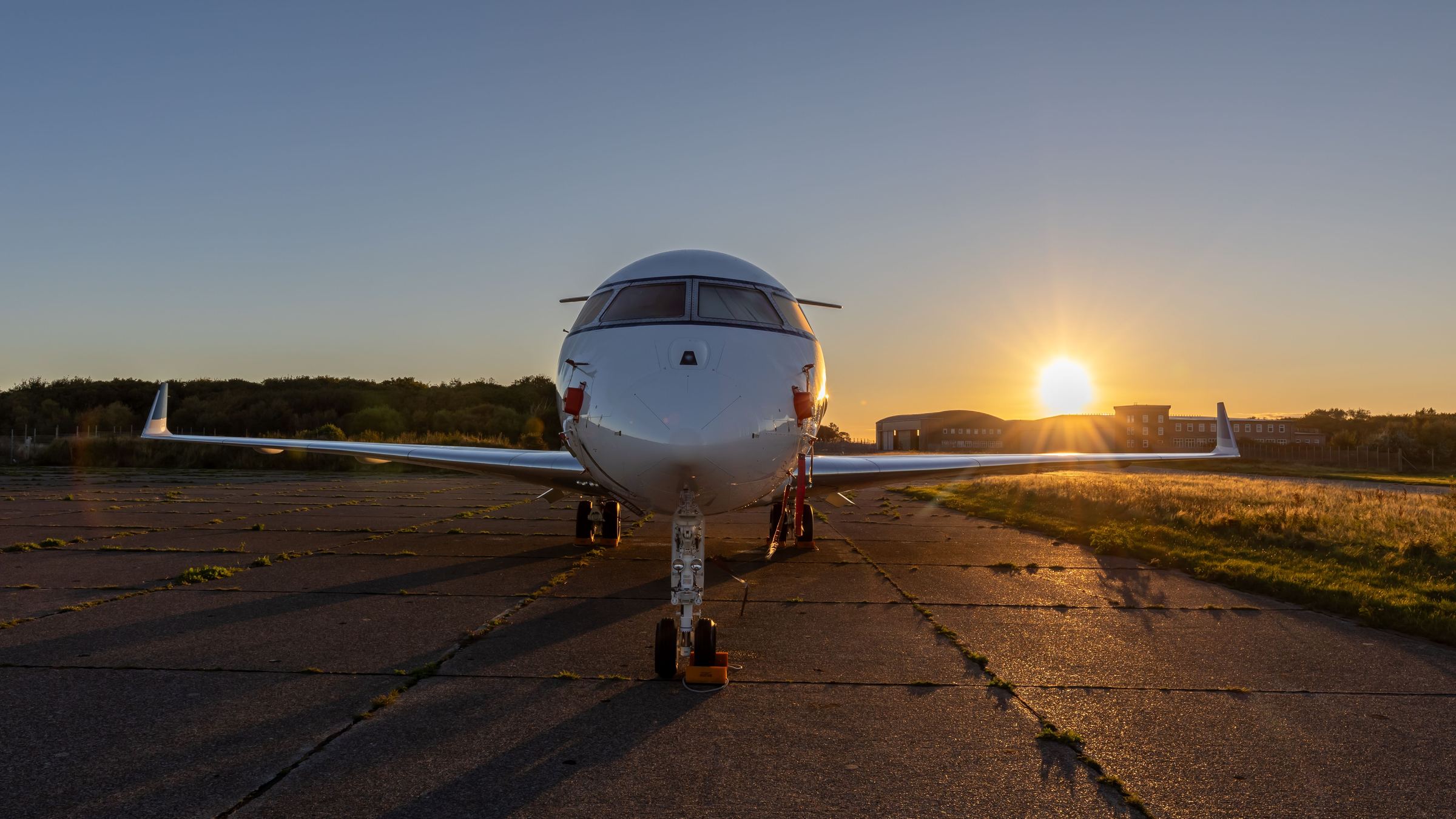 A business jet head-on on an apron at sunset.