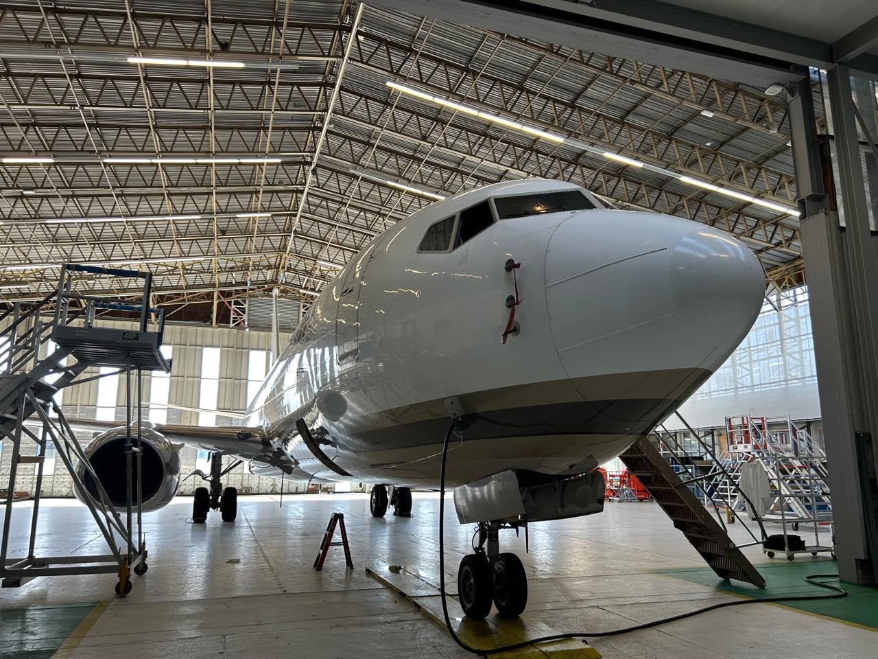 A white Boeing jet in a hangar with access stands around it.