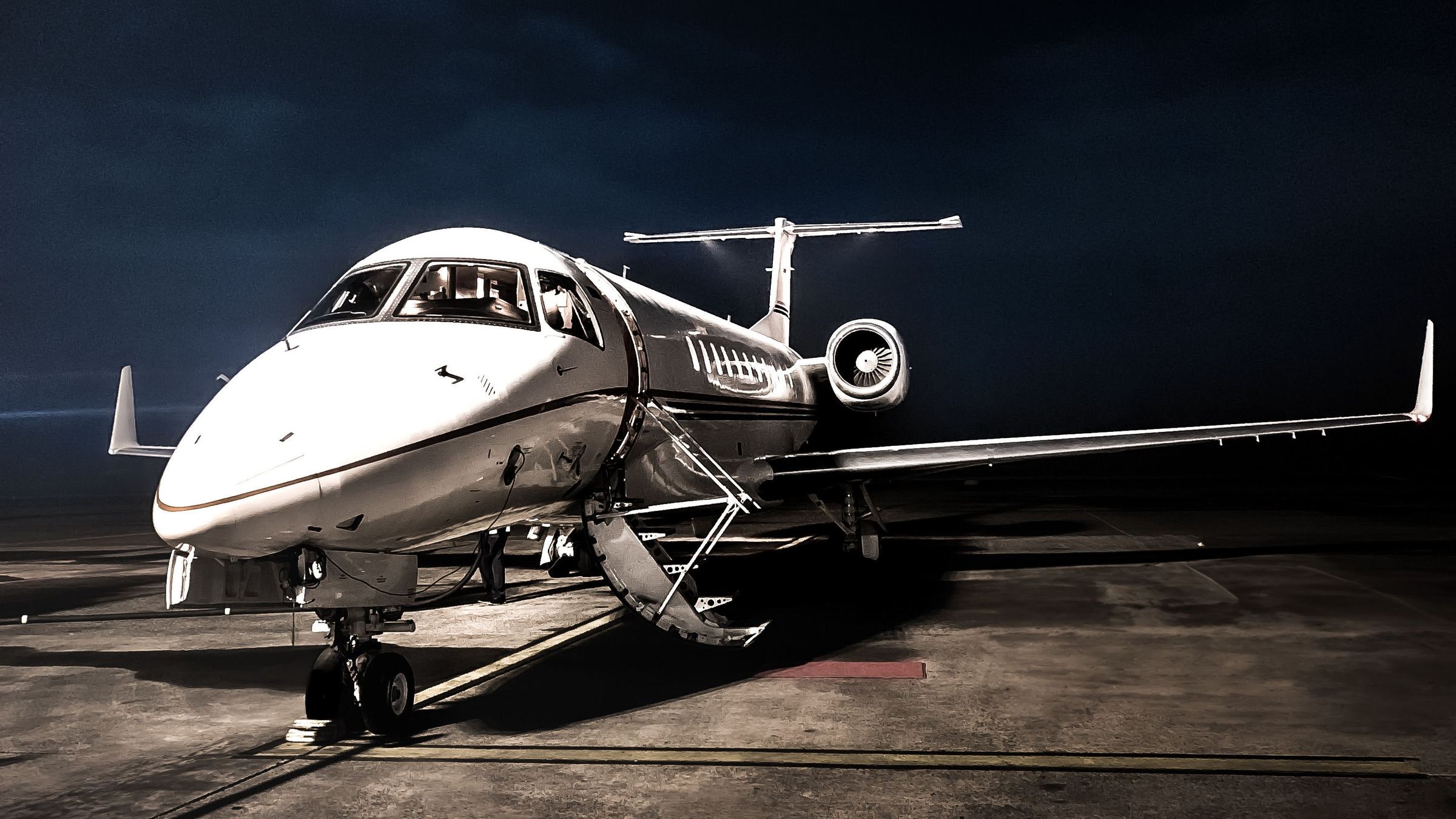 A business jet with its airstair down on a night apron.