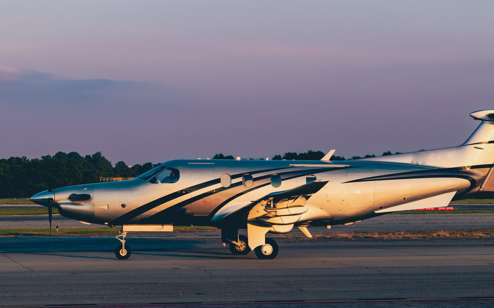 A Pilatus PC-12 turboprop on an apron at sunset. Stock photograph.