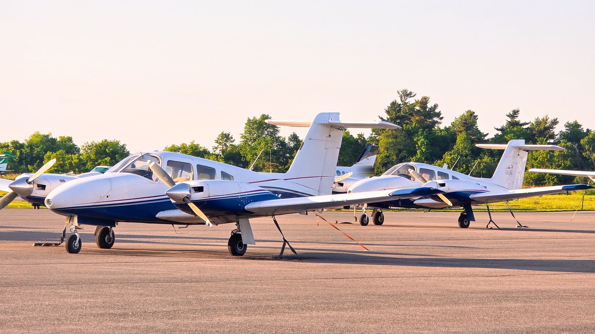 A grass airfield with light aircraft near the strip on a clear day.