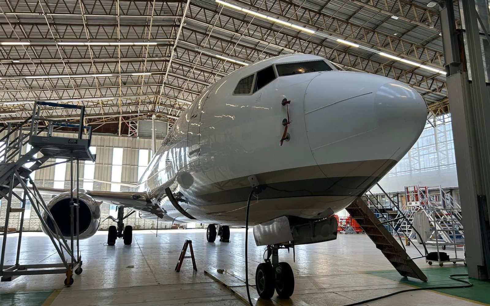 A Boeing 737 freighter in a maintenance hangar, nose-on, at an aircraft acceptance inspection